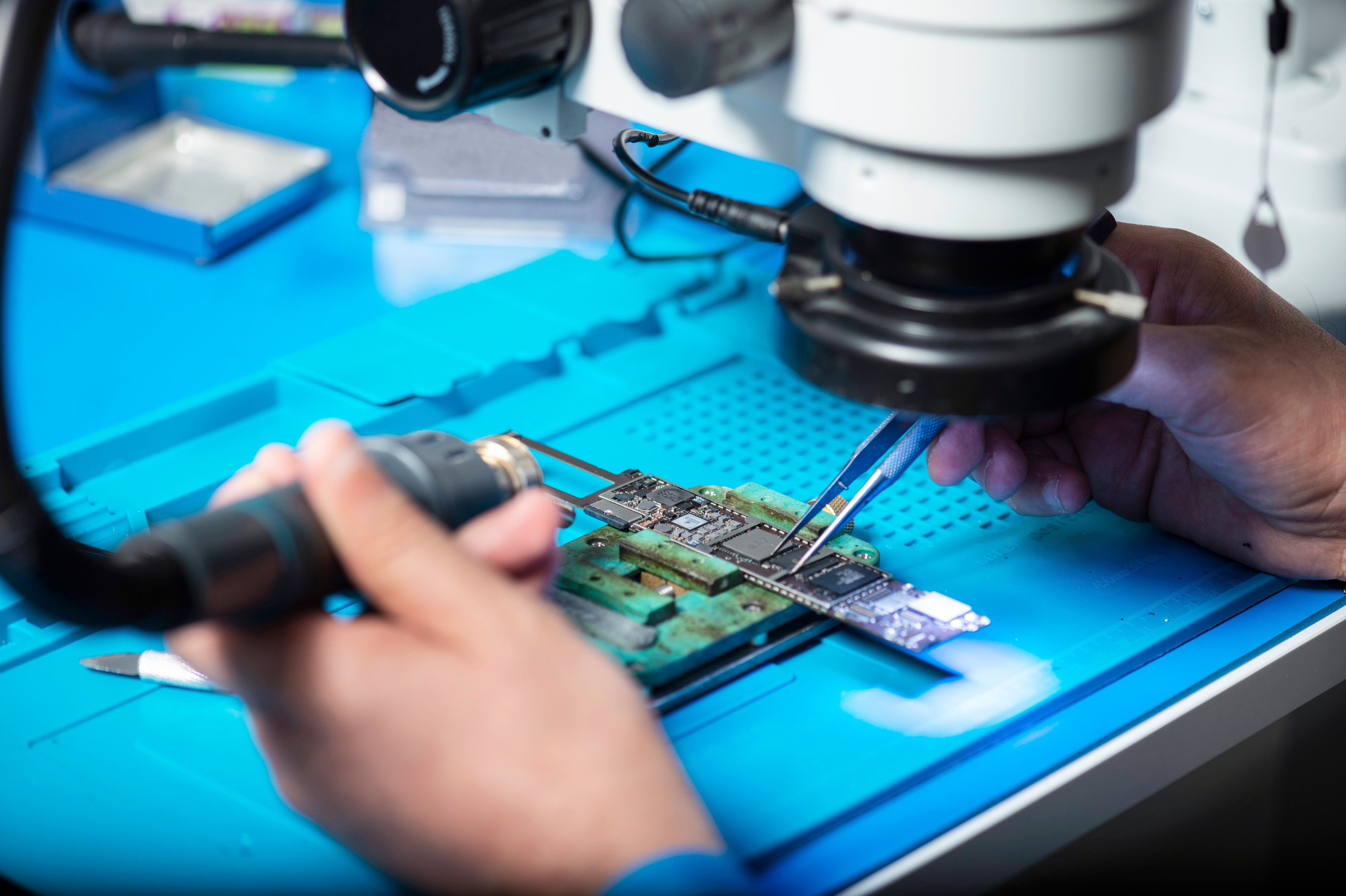 Technician inspecting a connected product circuit board under a microscope